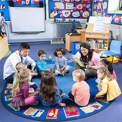 Students sitting in a circle with two teachers.