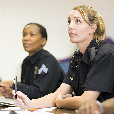 Two uniformed law enforcement officers, one a sergeant, during a briefing.