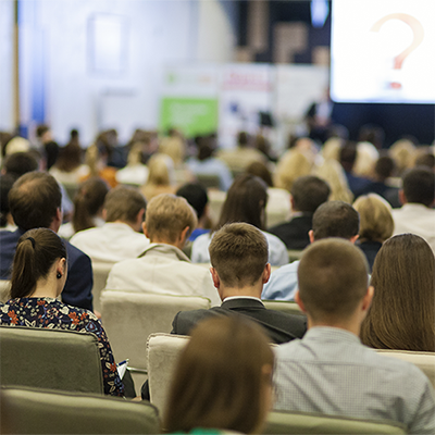 Person speaking to a large crowd at a seminar or training session.