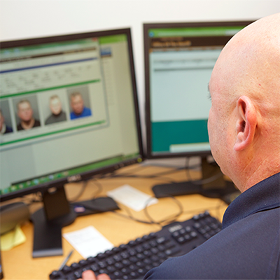 Officer looking at mugshots on a computer screen.